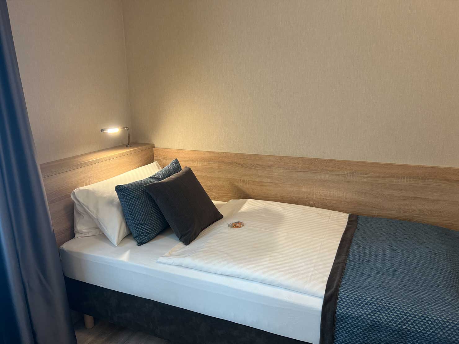 Modern eingerichtetes Komfort-Einzelzimmer in der Aal-Kate mit Einzelbett, Schreibtisch und warmem Licht für einen entspannten Aufenthalt.