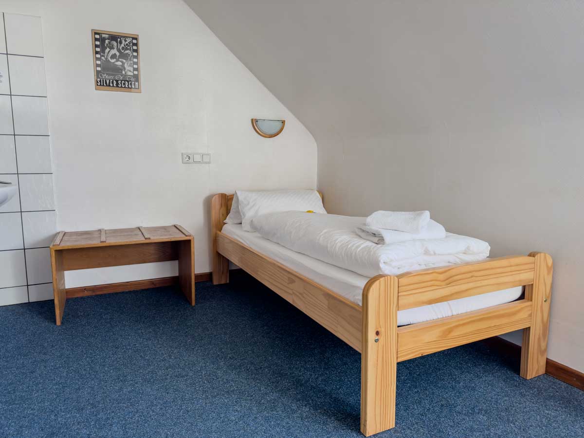 Economy-Einzelzimmer in der Aal-Kate Wuppertal mit Einzelbett, Waschbecken, Holzmöbeln und funktionaler Ausstattung für preisbewusste Gäste.