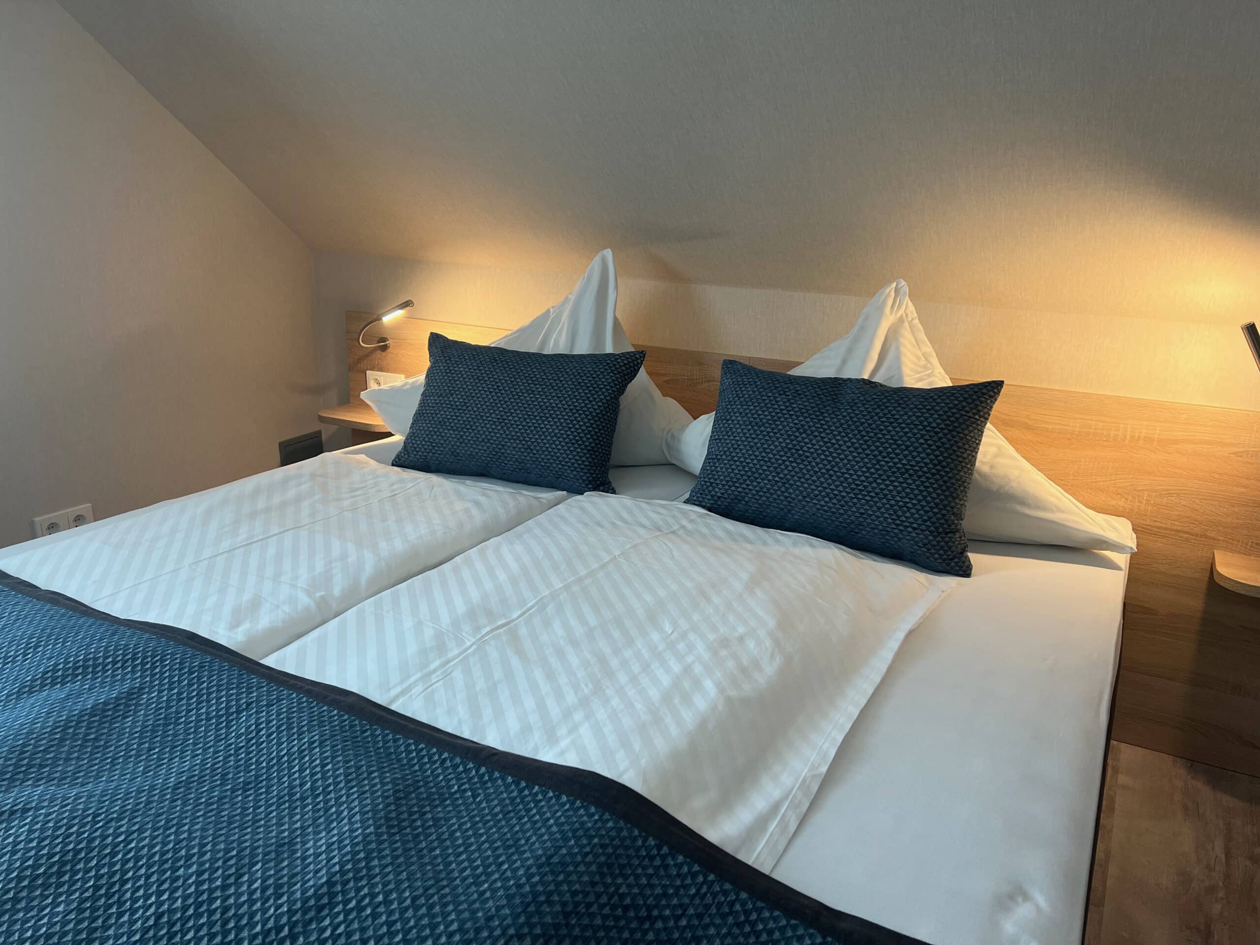 Modern eingerichtetes Komfort-Doppelzimmer in der Aal-Kate Wuppertal mit gemütlichem Doppelbett, stilvoller Beleuchtung und Dachschräge.